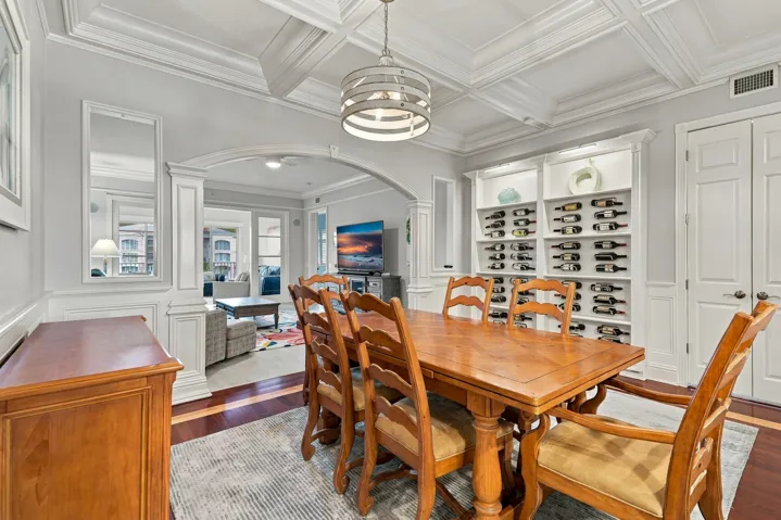 This condo features so many upgrades. Dining room has wood flooring with an inlay, custom wine rack, coffered ceiling, crown molding, archway, and stylish lighing.