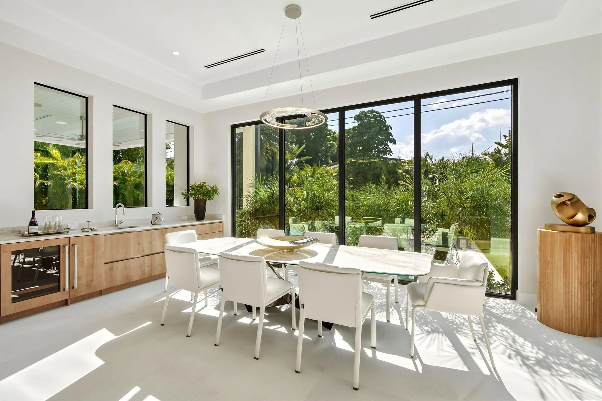 Expansive floor-to-ceiling windows, built-in bar with under-counter beverage cooler, recessed lighting, and a modern chandelier