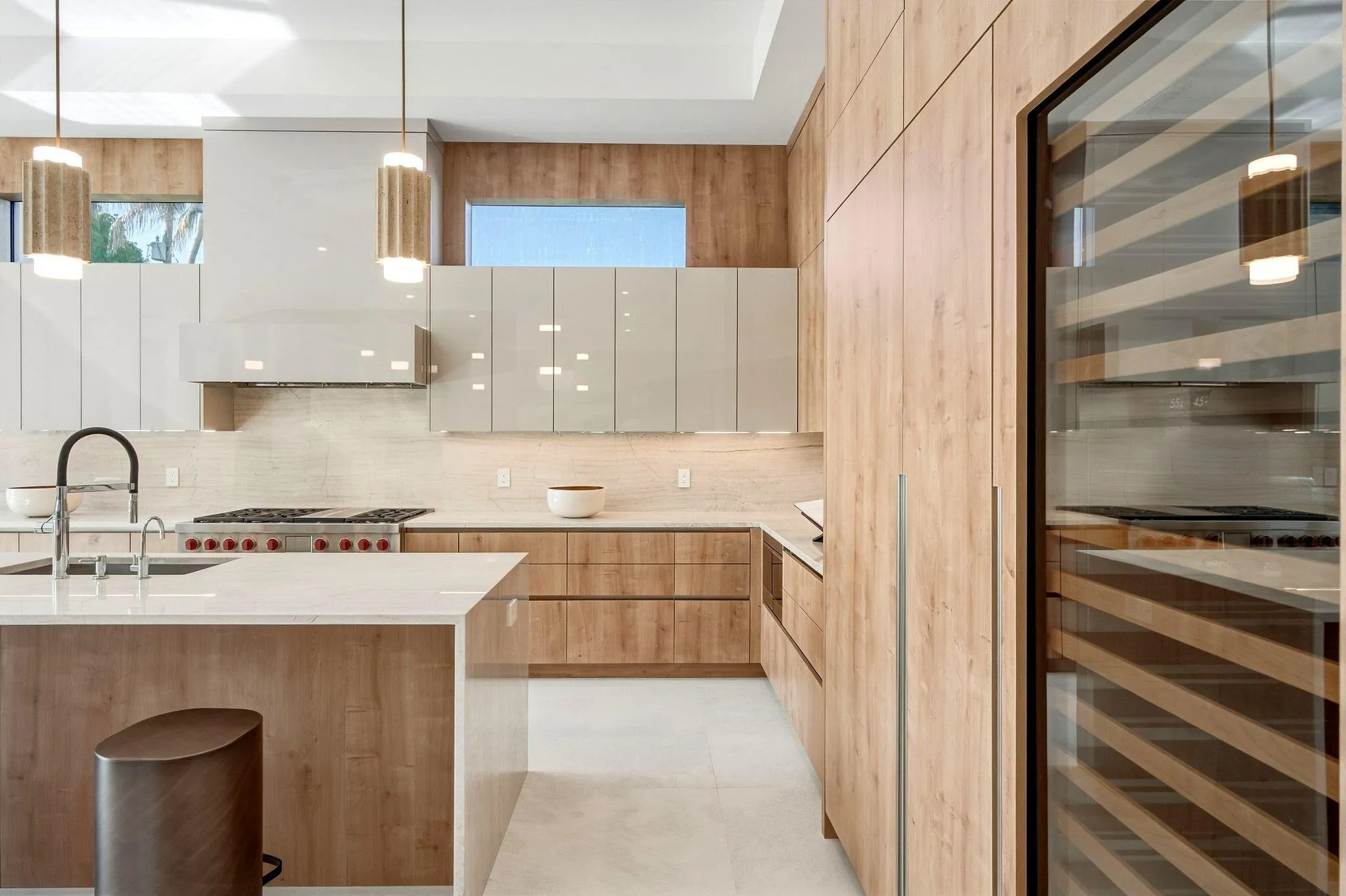 Modern kitchen featuring wood-finish cabinetry, light-toned countertops, and a built-in wine refrigerator