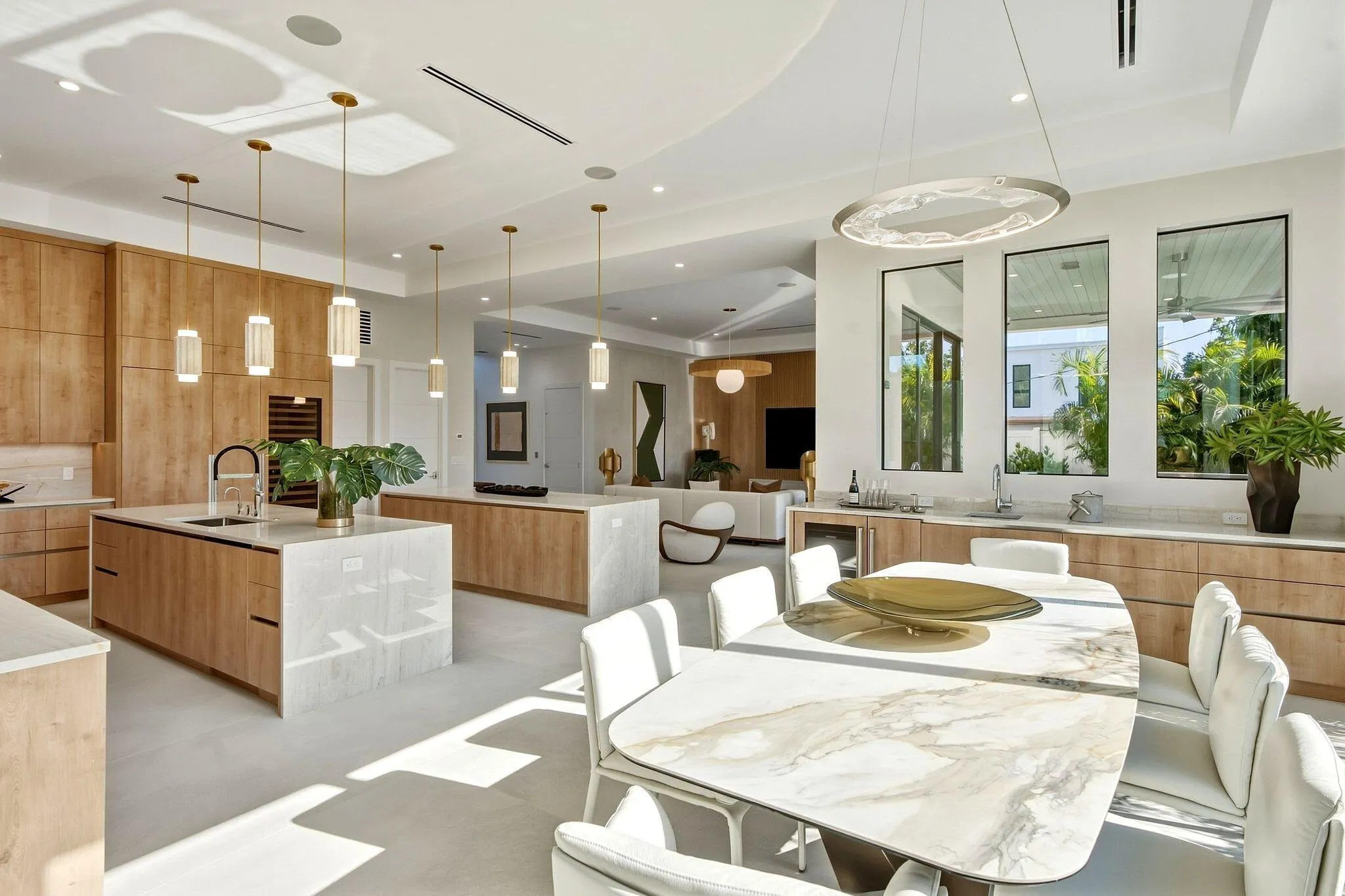 Open-concept kitchen and dining area featuring dual islands with waterfall countertops, integrated appliances, and floor-to-ceiling cabinetry