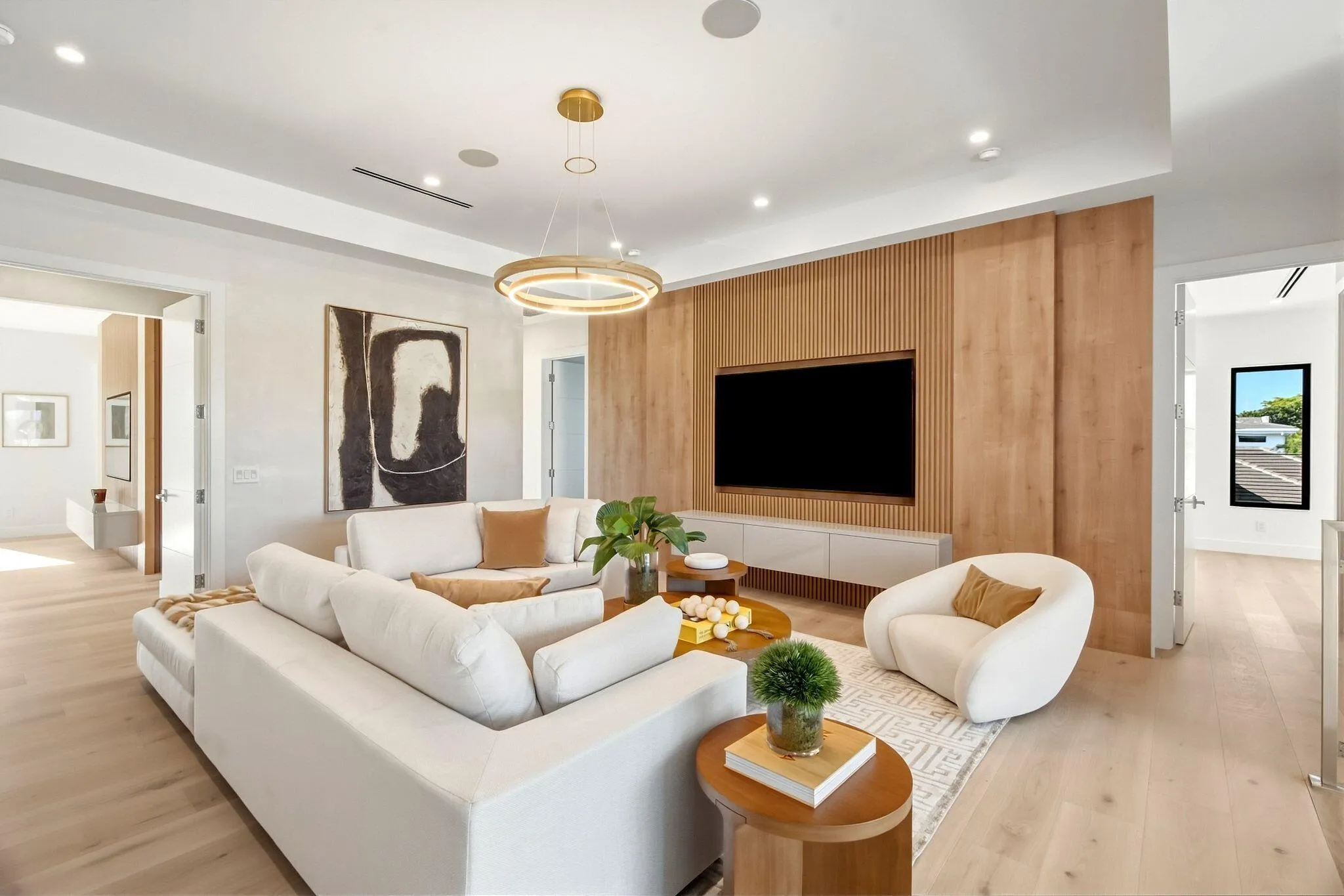 Recessed lighting, wood-finish flooring, a contemporary chandelier, a built-in media console, and a wood-slat accent wall