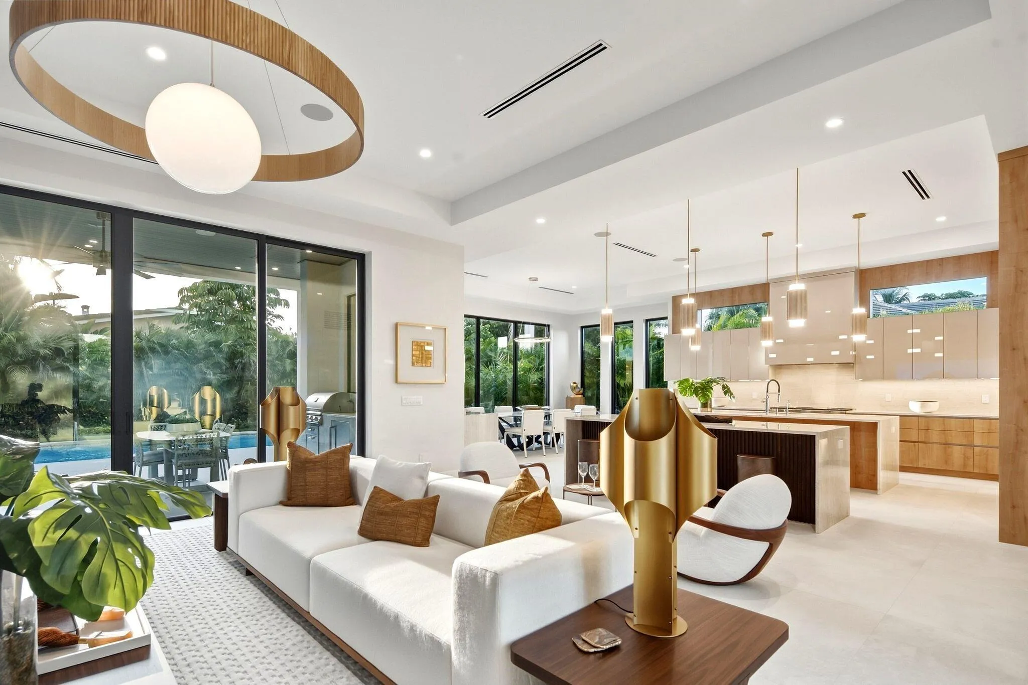 Expansive sliding glass doors, integrated kitchen cabinetry, recessed ceiling lighting, a large kitchen island, and contemporary pendant fixtures