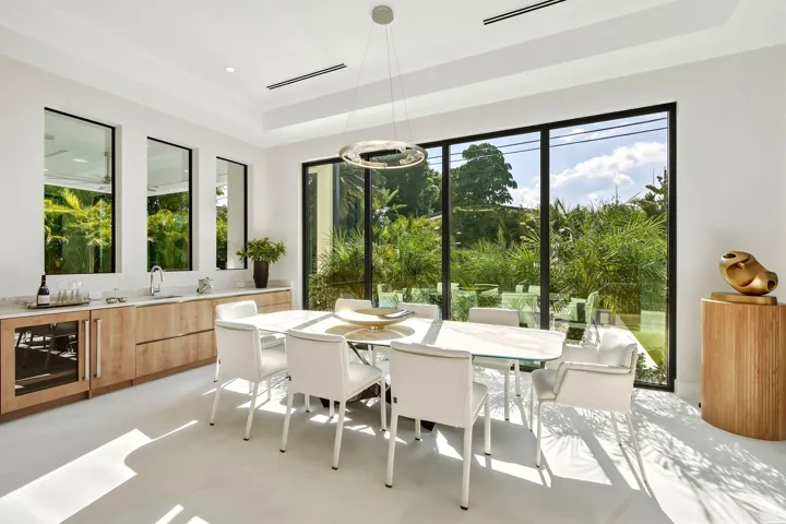 Expansive floor-to-ceiling windows, built-in bar with under-counter beverage cooler, recessed lighting, and a modern chandelier