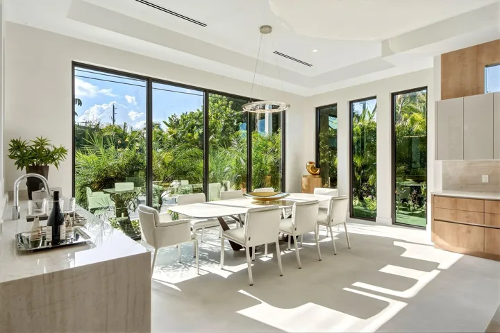 Expansive floor-to-ceiling windows, built-in light wood cabinetry, stone countertops, recessed lighting, and a contemporary chandelier