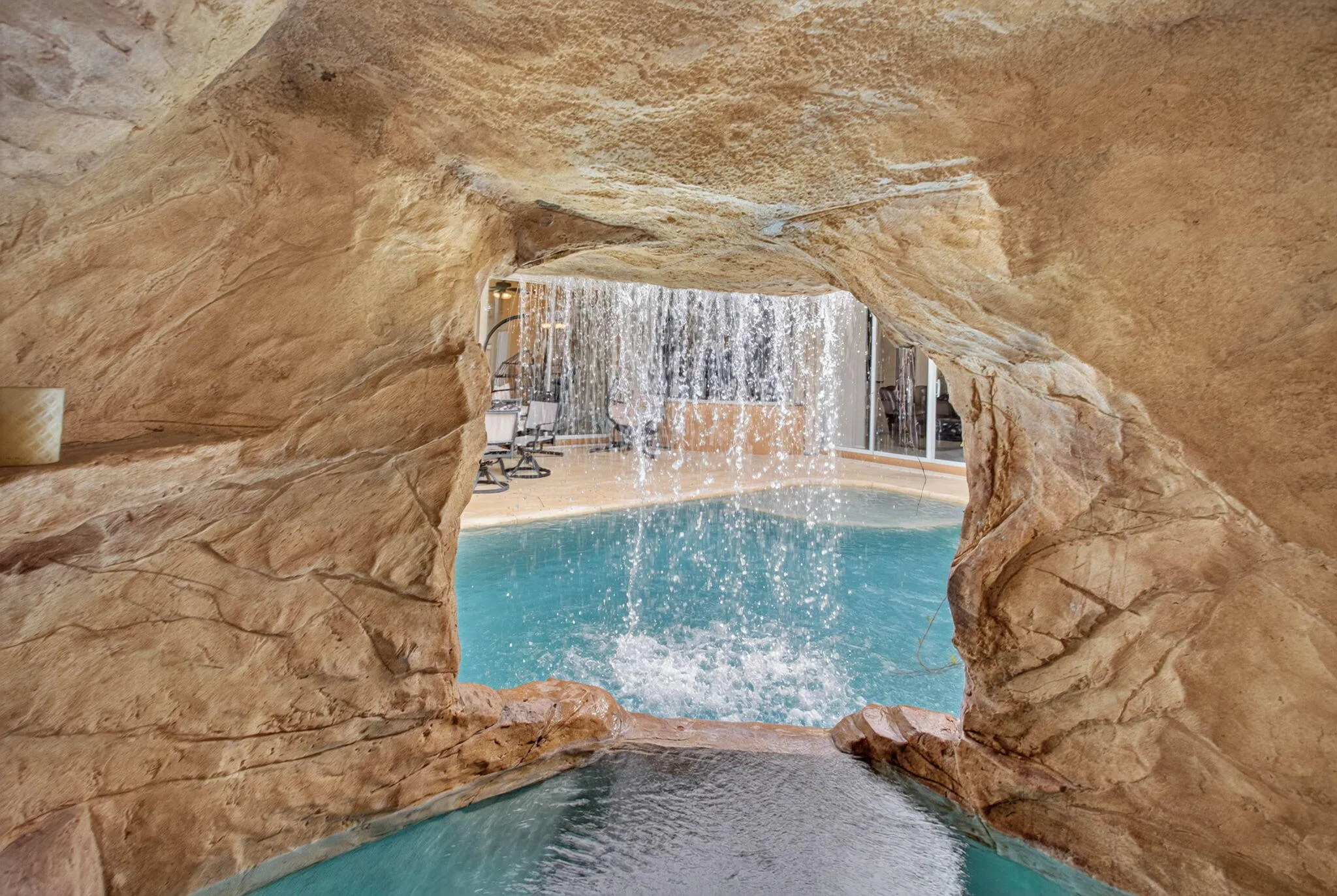Pool Deck. View from cave entrance looking out beneath waterfall and behind the built in hot tub Jacuzzi. Hot tub and waterfall operate off a separate variable speed pump and can be heated to 102 degrees. The electric heater can heat both the pool and the Jacuzzi and everything can be set to diferrant speeds and time via remote control.