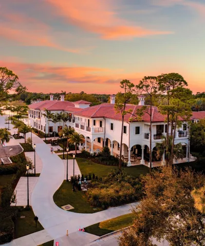 Mediterranean-inspired architecture with a red tile roof, white stucco exterior, multiple arched verandas, and mature landscaping