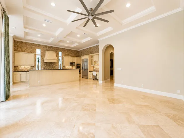 Expansive open-concept living area featuring large format tile flooring, a coffered ceiling with recessed lighting, and a contemporary ceiling fan