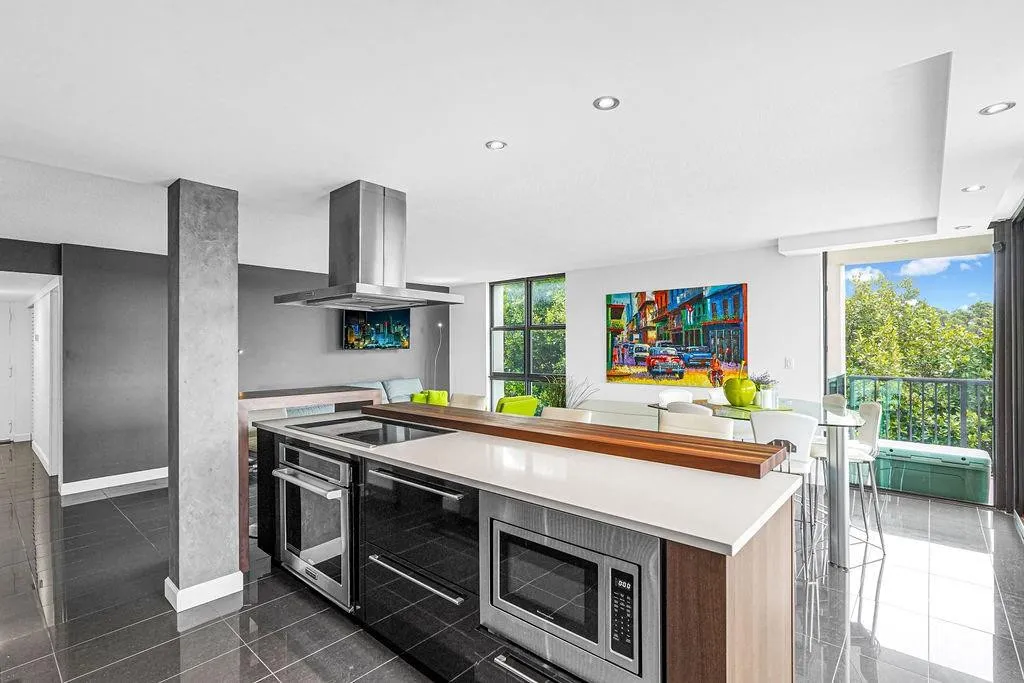 Open kitchen with white quartz & wood accent counter.