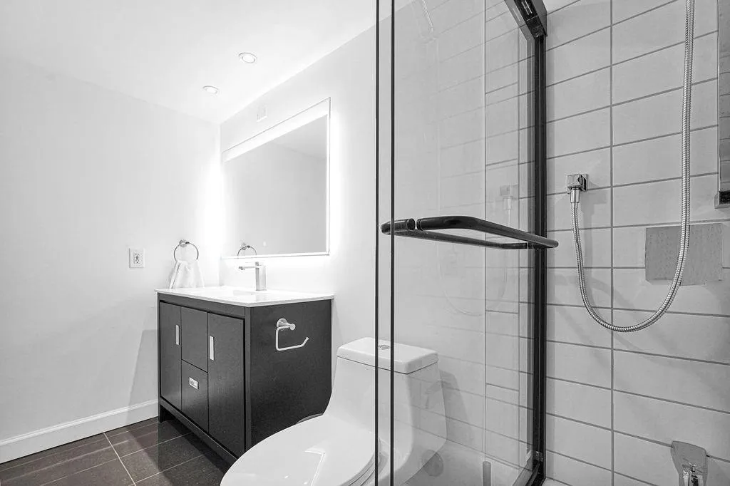 White tile, chic vanity & backlit mirror.