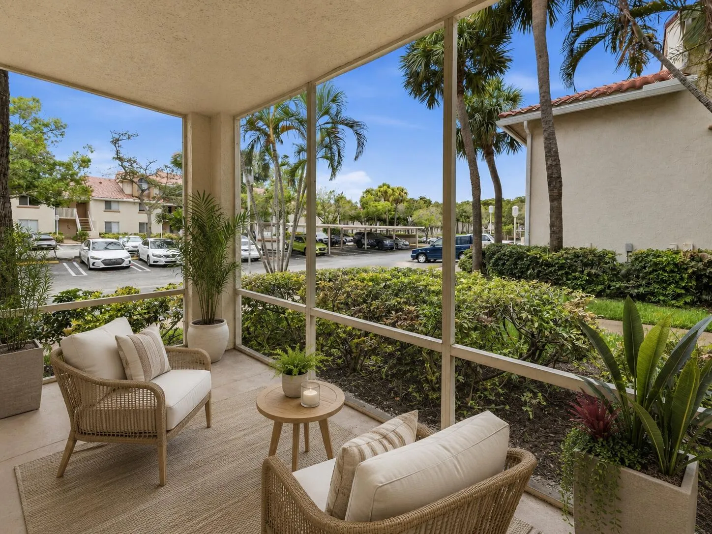 Screened patio featuring a concrete floor, lush tropical landscaping, and mature palm trees