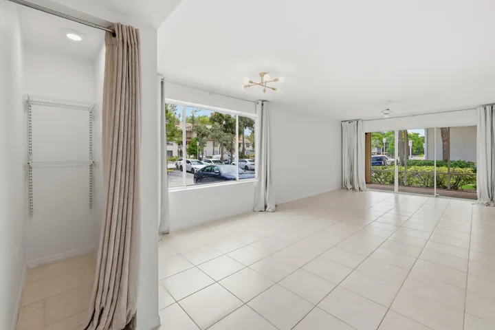 Spacious room featuring neutral tile flooring, a modern sputnik-style ceiling fixture, and a large window providing ample natural light
