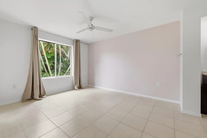 Primary bedroom featuring neutral tile flooring and a large window overlooking lush tropical foliage
