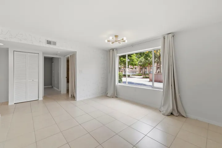 Bright living space featuring large format tile flooring, a modern sputnik light fixture, and a wide window with exterior landscaping
