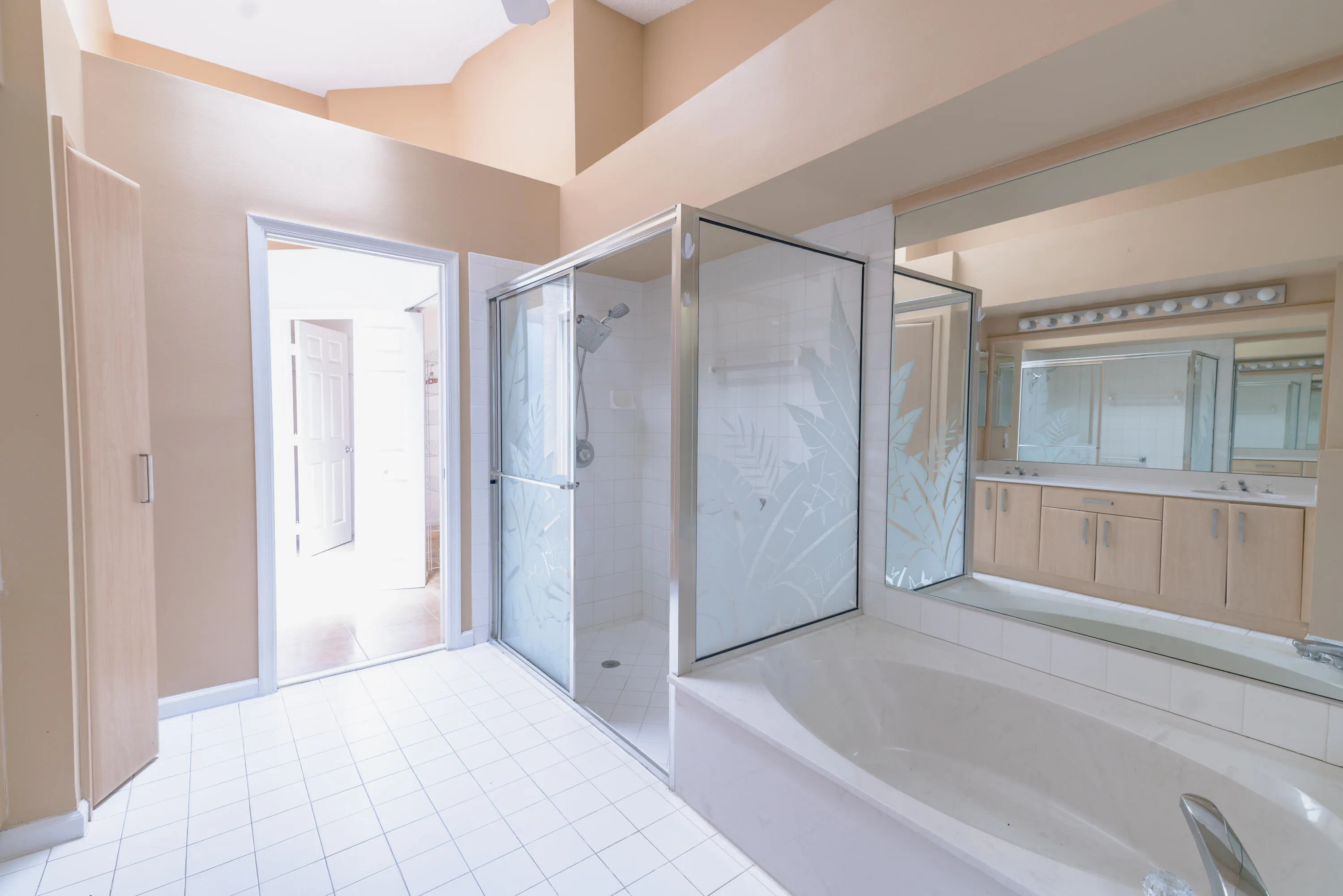 Recessed tub with tiled surround, walk-in shower with etched glass enclosure, double vanity with integrated sinks, and tiled flooring