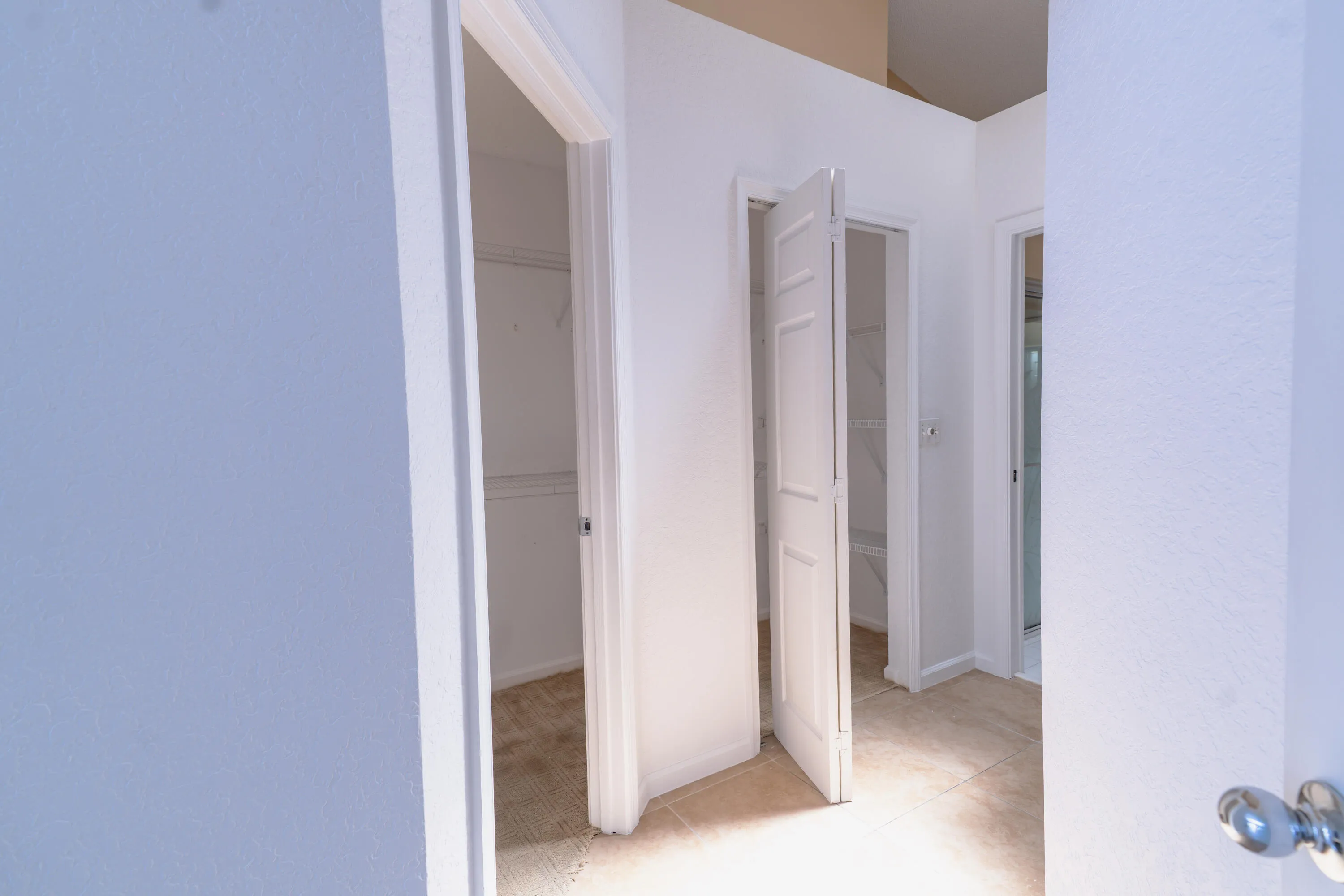 Multiple entryways with white paneled doors, light tile flooring, and carpeted interior spaces