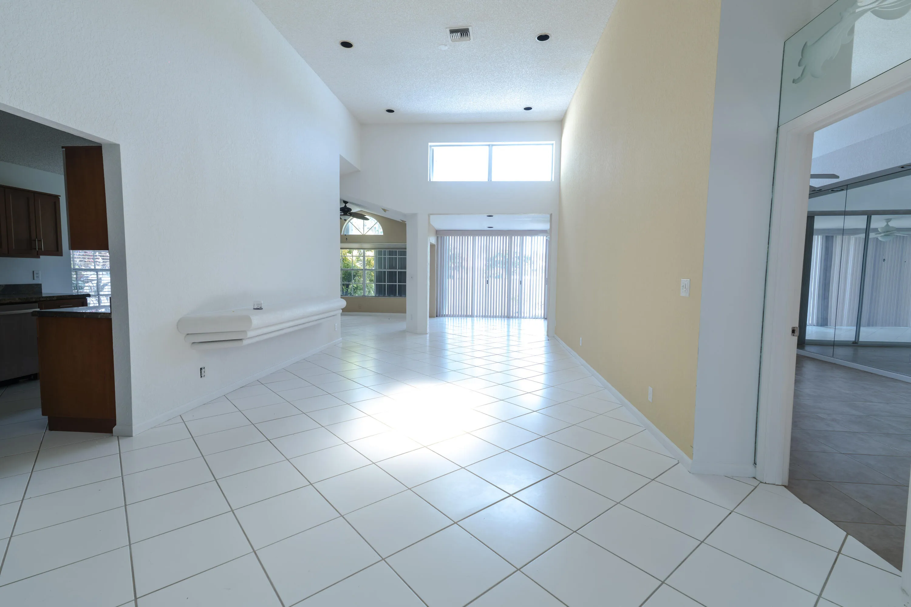 High ceilings, recessed lighting, and white tile flooring