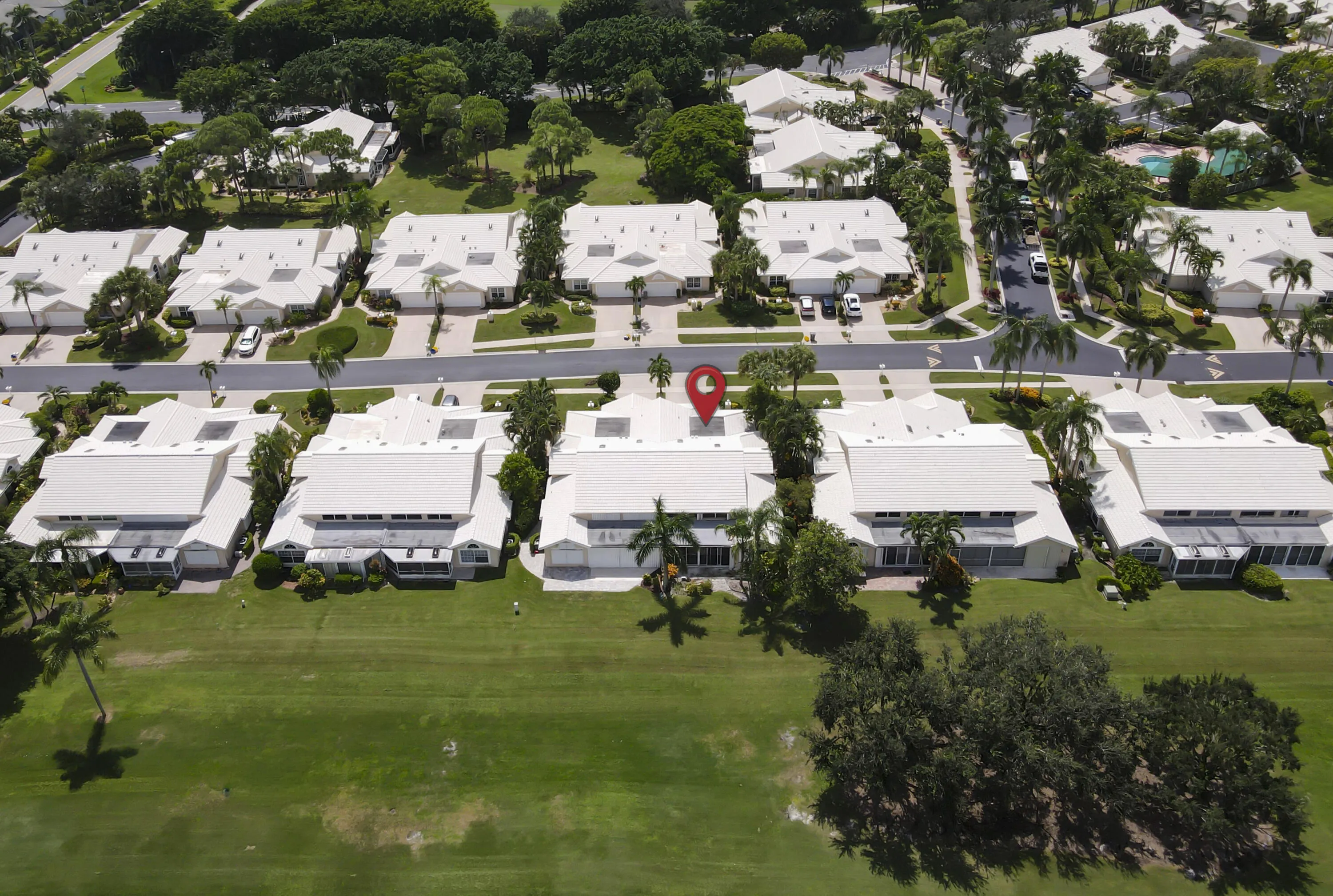 Residential community with white-roofed properties, fronting a large expanse of green space