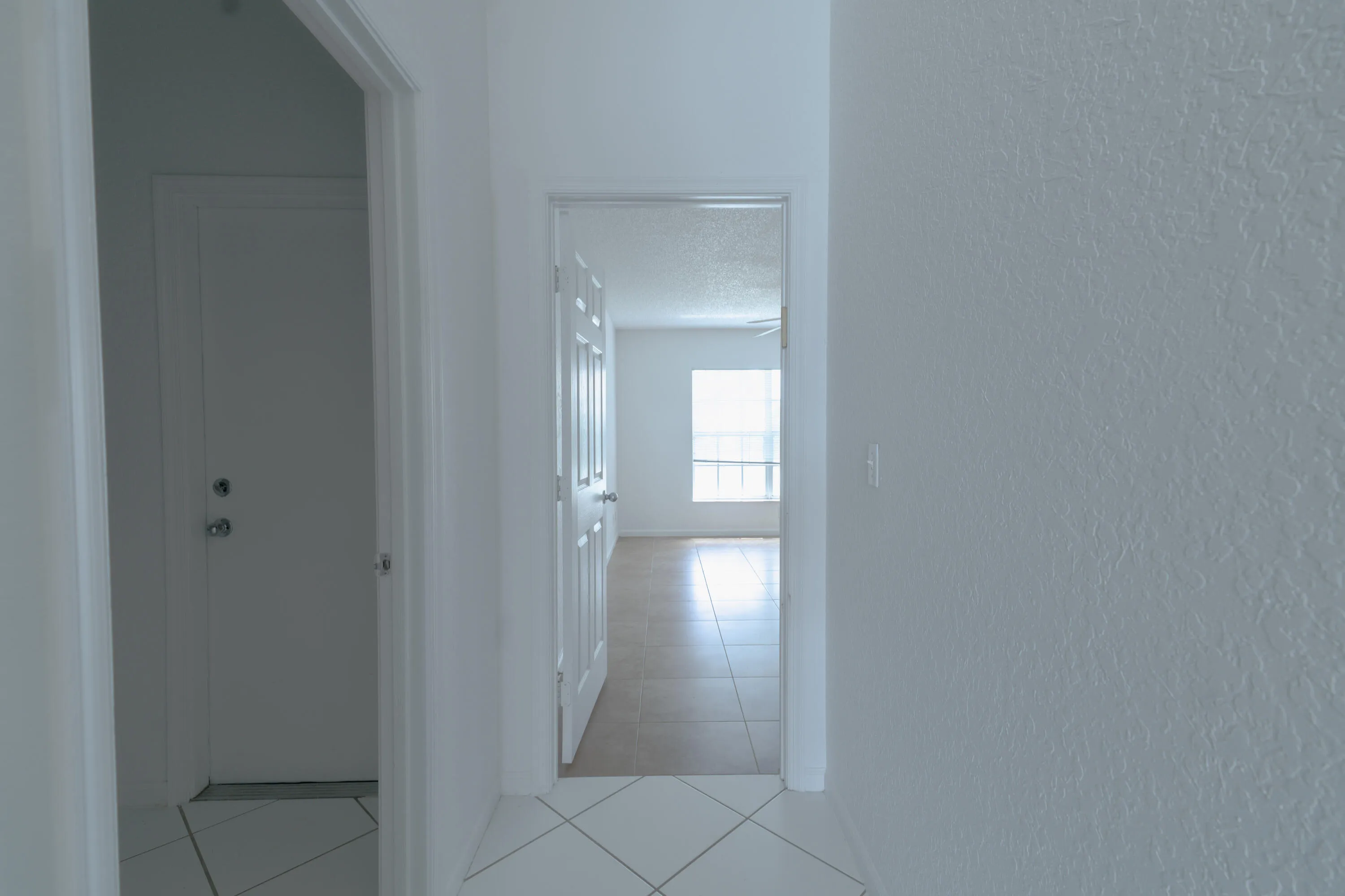 White interior walls with textured finish, white interior doors, and tile flooring