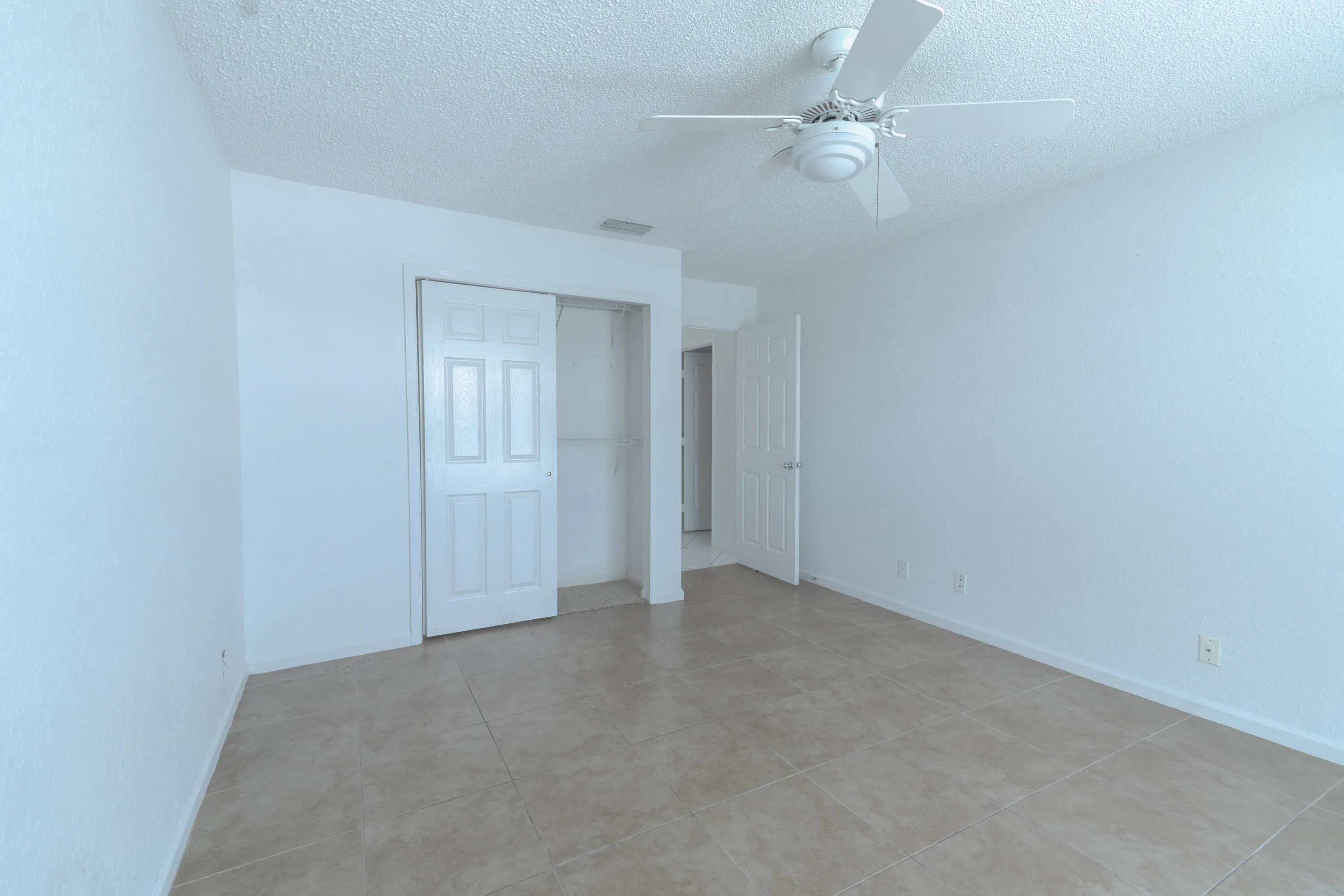 Ceramic tile flooring, white walls, white paneled closet doors, ceiling fan, and white trim