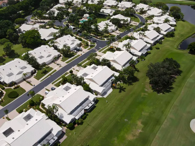 Residential development featuring white-roofed homes, paved streets, and manicured landscaping