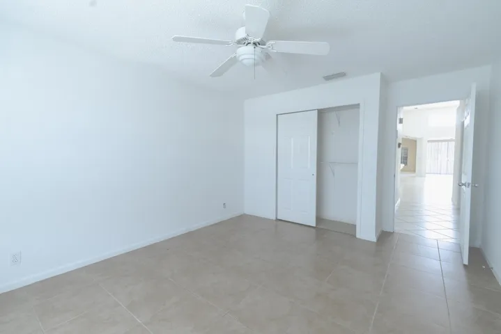 Tile flooring, ceiling fan, and white walls