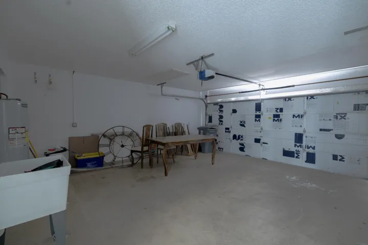 Spacious garage with an insulated garage door, concrete flooring, and a utility sink
