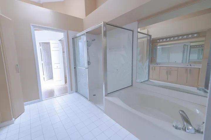 Tiled flooring, built-in soaking tub, glass-enclosed shower, dual vanity, and overhead lighting