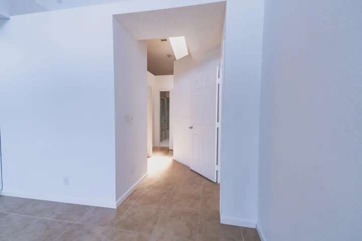Recessed lighting illuminating a hallway with tile flooring and a paneled interior door