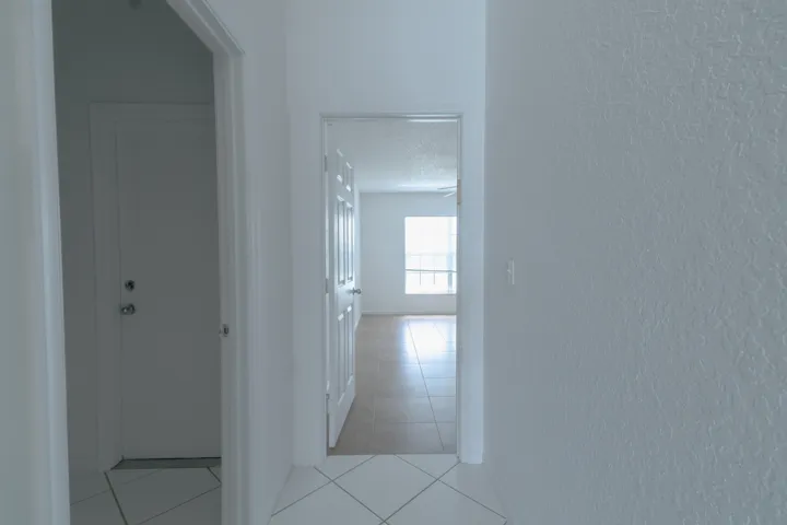 White interior walls with textured finish, white interior doors, and tile flooring