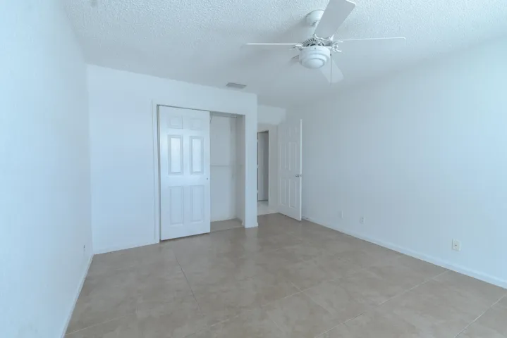 Ceramic tile flooring, white walls, white paneled closet doors, ceiling fan, and white trim