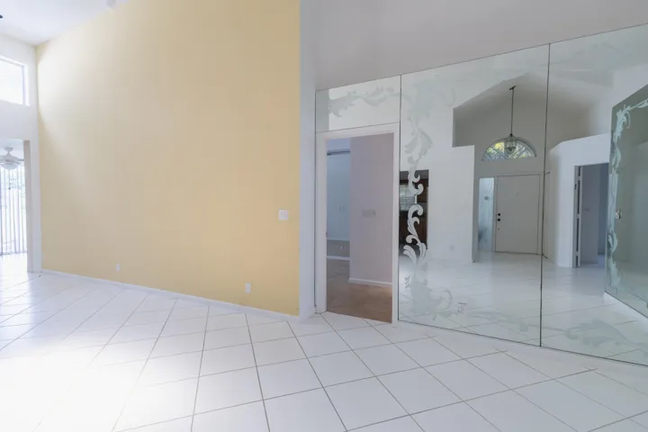 Vaulted ceilings, light-toned tile flooring, mirror wall with etched detailing, and transom window