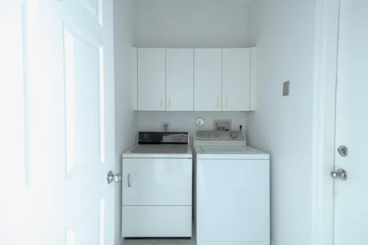 Dedicated utility area with white upper cabinetry and a paneled door