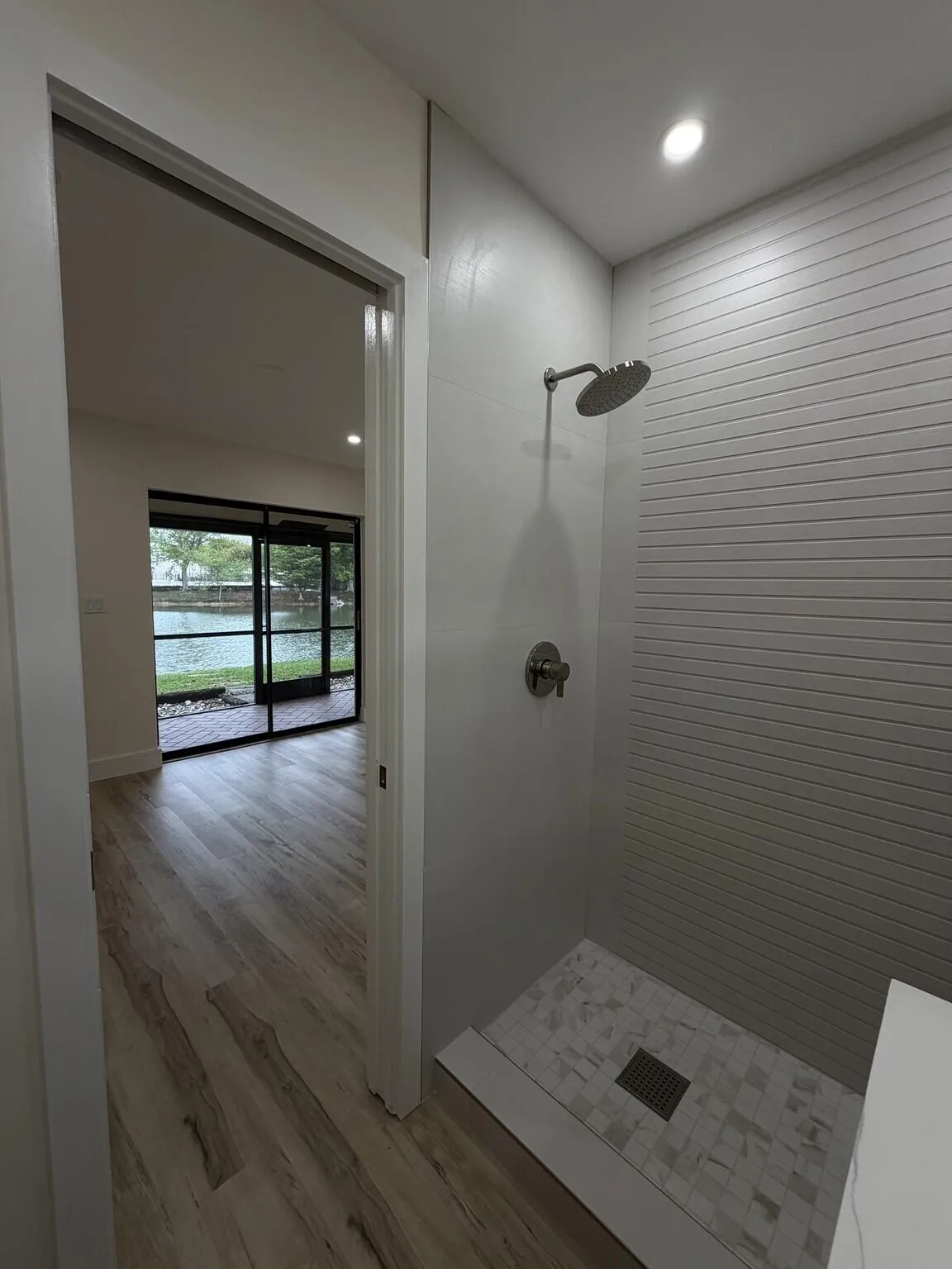 Walk-in shower with mosaic tile flooring and textured wall tile