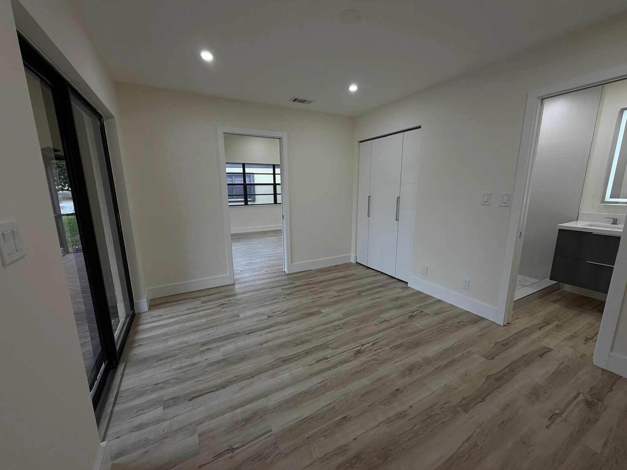 Wood-finish flooring throughout, recessed lighting, and a sliding glass door