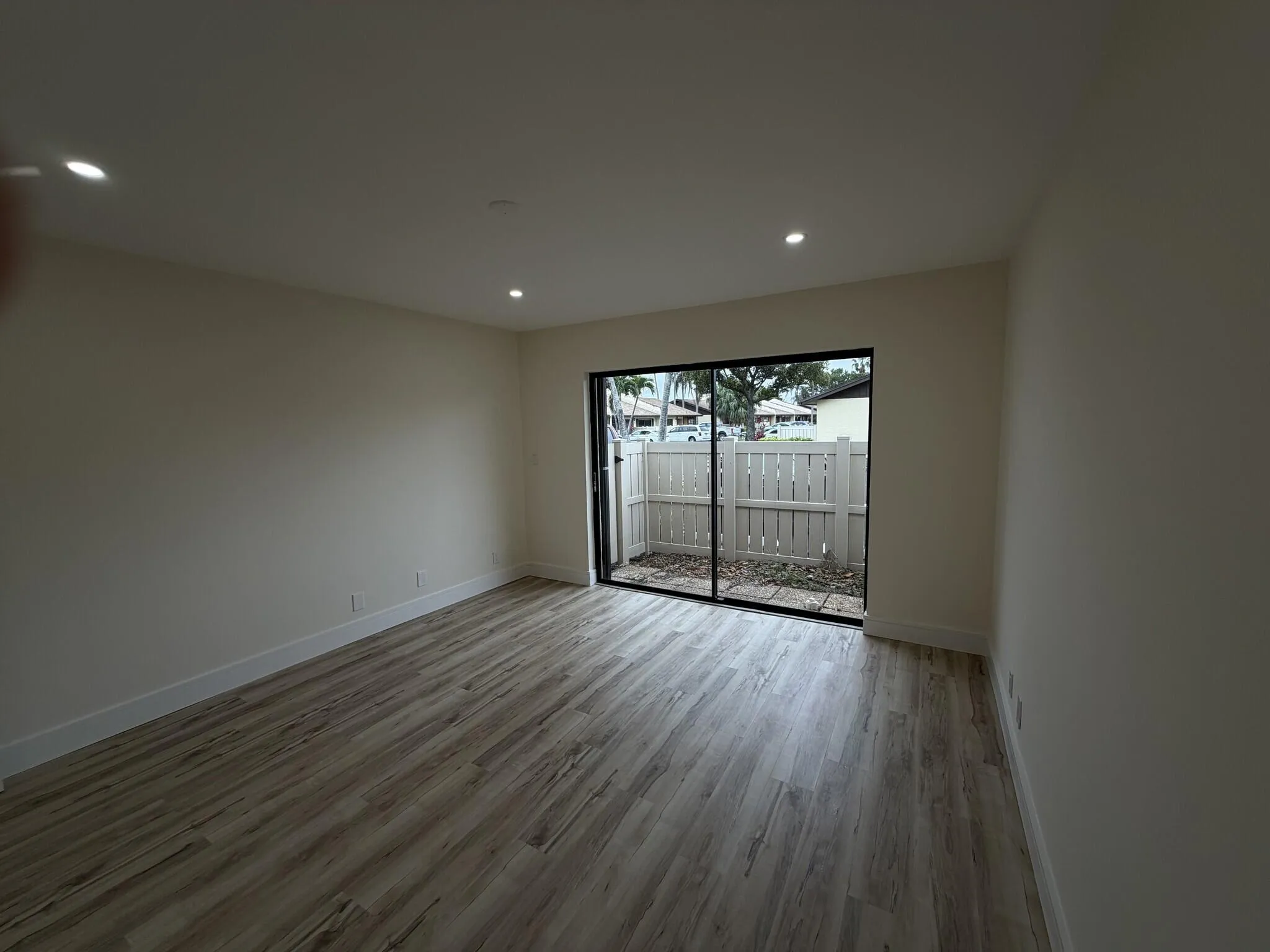 Recessed lighting, wood-finish flooring, sliding glass door, private outdoor area, and perimeter fencing