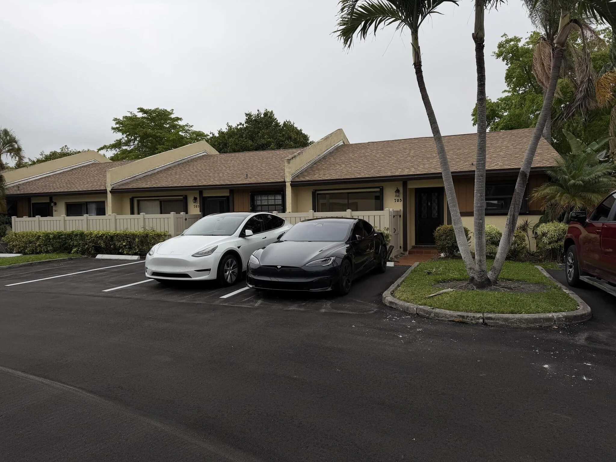Property exterior featuring a shingle roof, paved parking, and established landscaping
