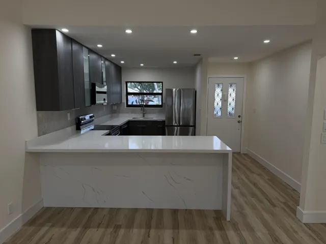 Kitchen featuring white countertops, stainless steel appliances, dark wood-finish cabinetry, a textured backsplash, and recessed lighting