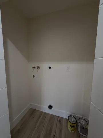 Dedicated laundry alcove featuring wood-finish flooring and integrated utility connections