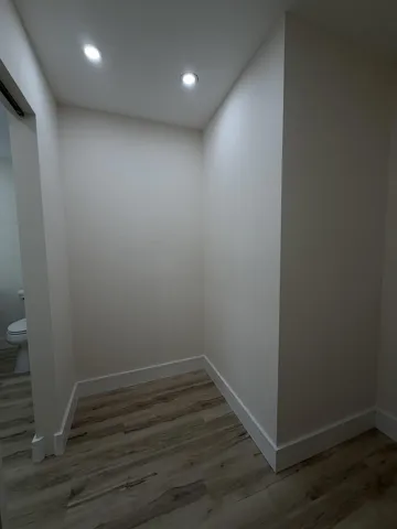 Recessed ceiling lighting, light-toned wall finishes, wood-finish flooring, and white trim