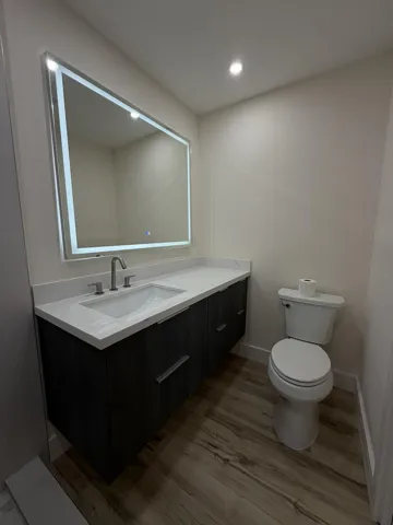 Floating vanity with an integrated sink, quartz countertop, and wood-finish flooring