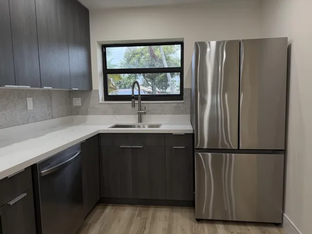 Kitchen featuring wood-finish cabinetry, stainless steel appliances, white countertops, and a tile backsplash