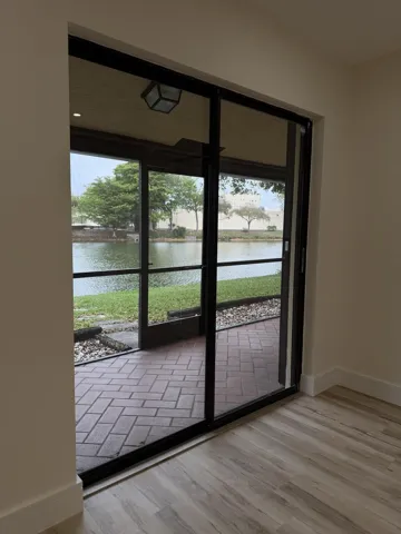 Sliding glass doors opening to a screened patio with paver flooring, overlooking a water feature