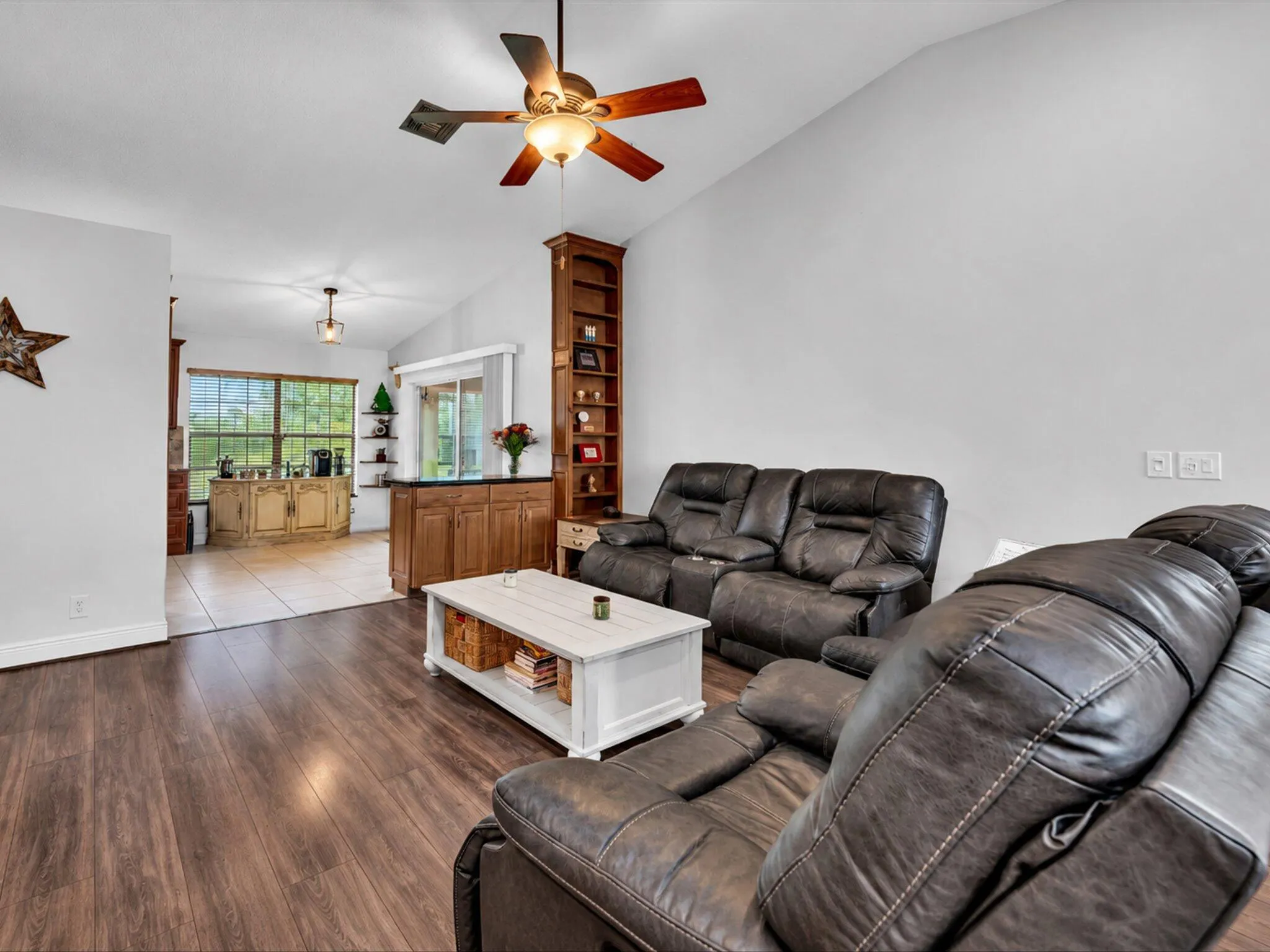 Vaulted ceiling with a ceiling fan, wood-finish flooring, built-in shelving, and a built-in cabinet