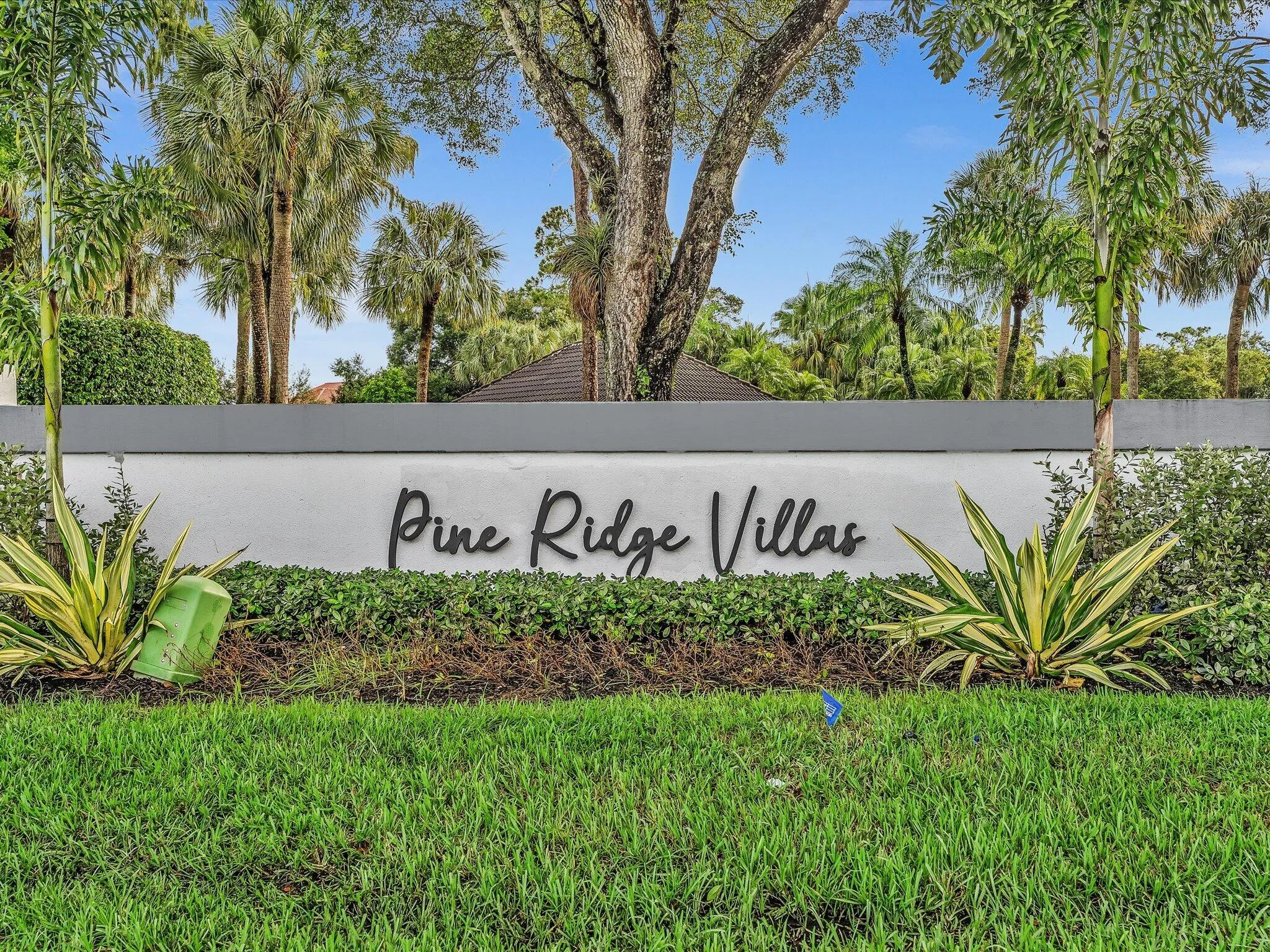 Pine Ridge Villas signage with surrounding mature landscaping and palm trees
