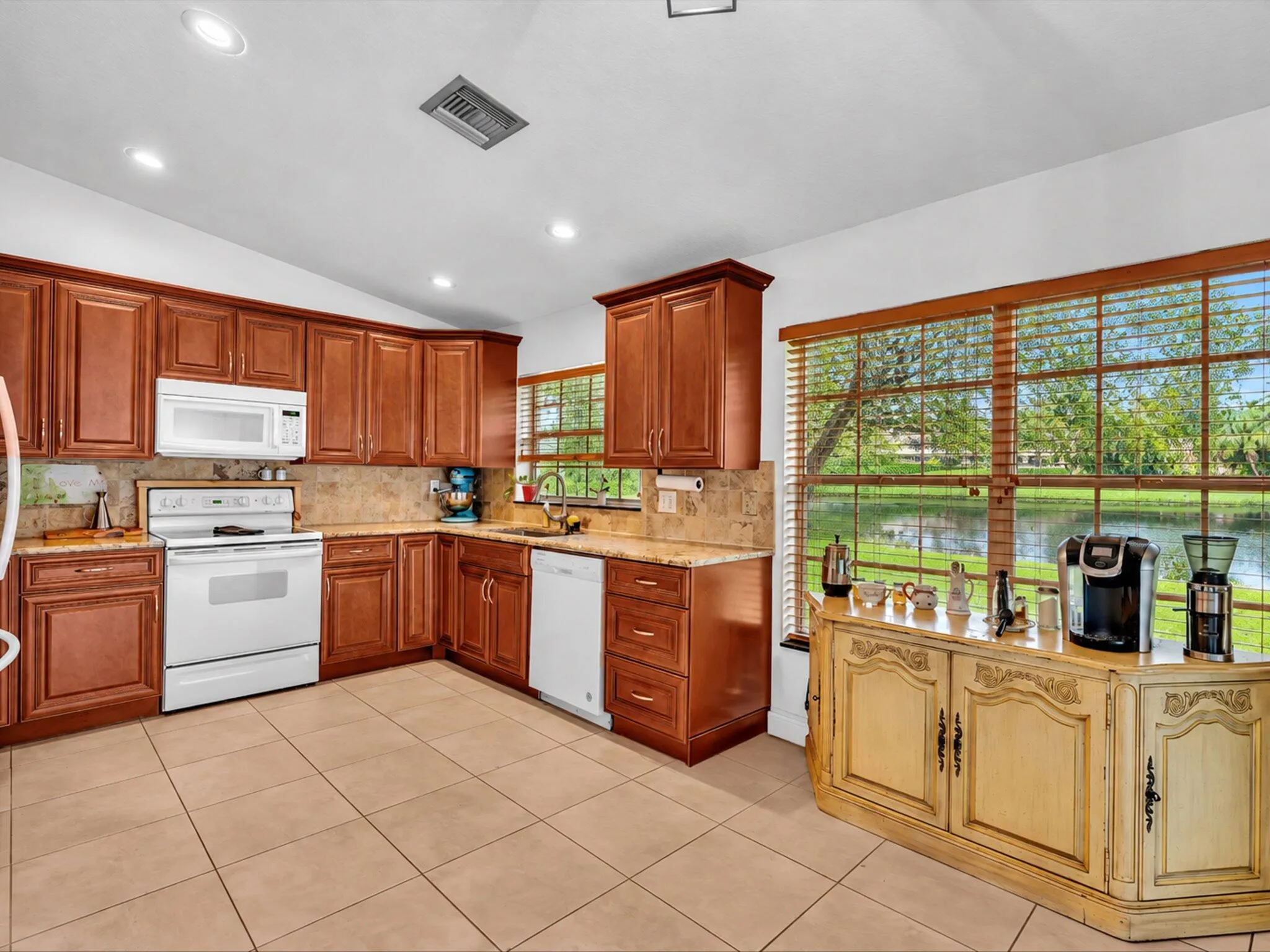 Kitchen featuring wood cabinetry, white appliances, tile flooring, and recessed lighting