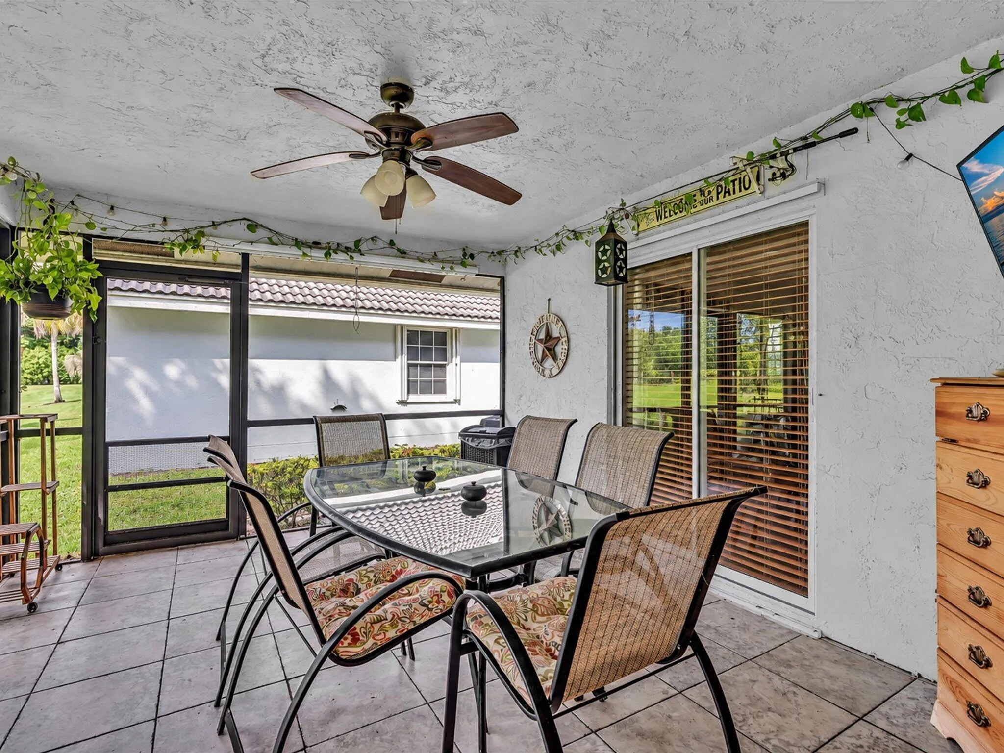 Screened outdoor living area with a ceiling fan, tiled flooring, and sliding glass doors