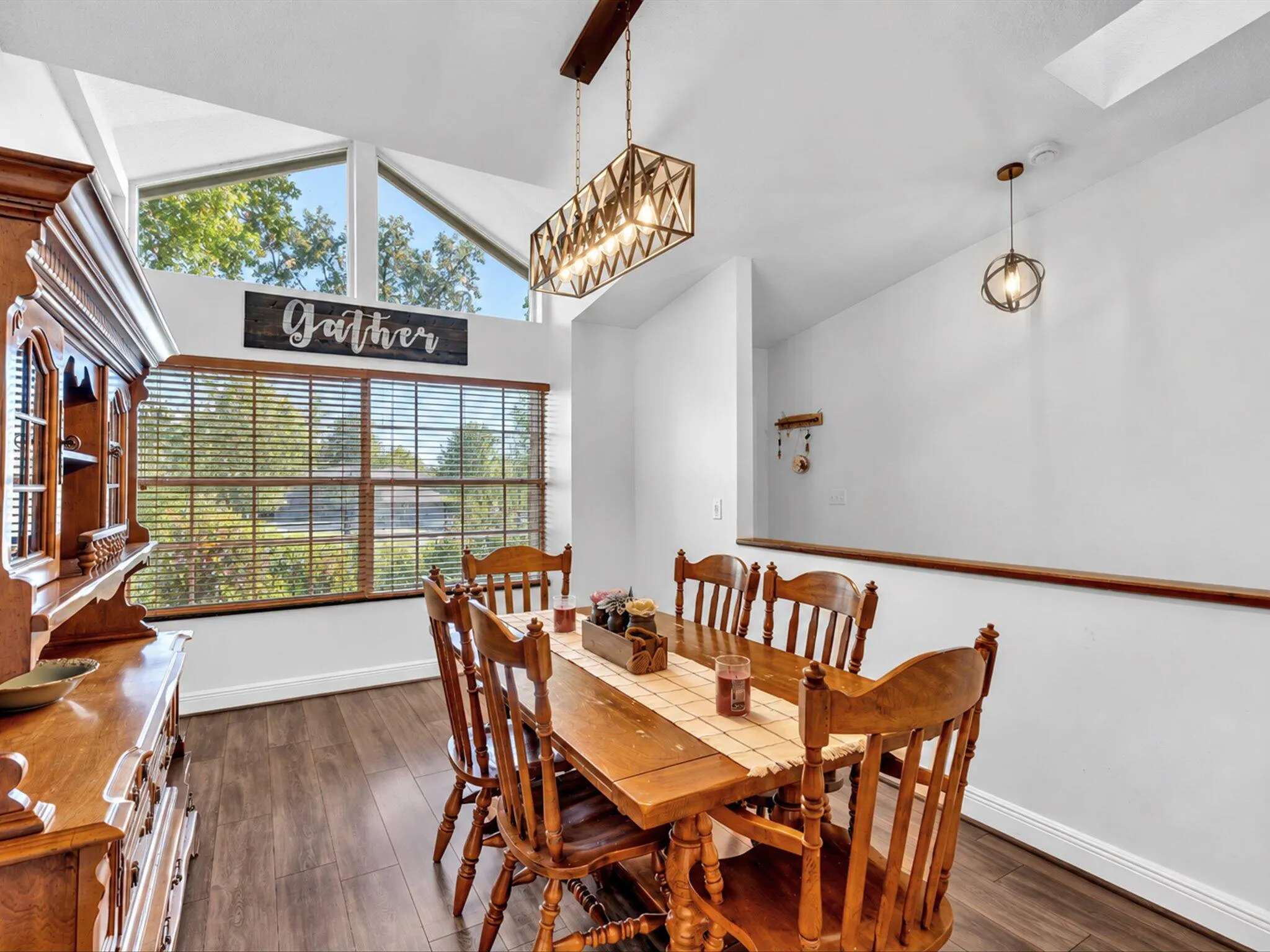 Vaulted ceiling with triangular windows, wood-finish flooring, and a large horizontal window with blinds