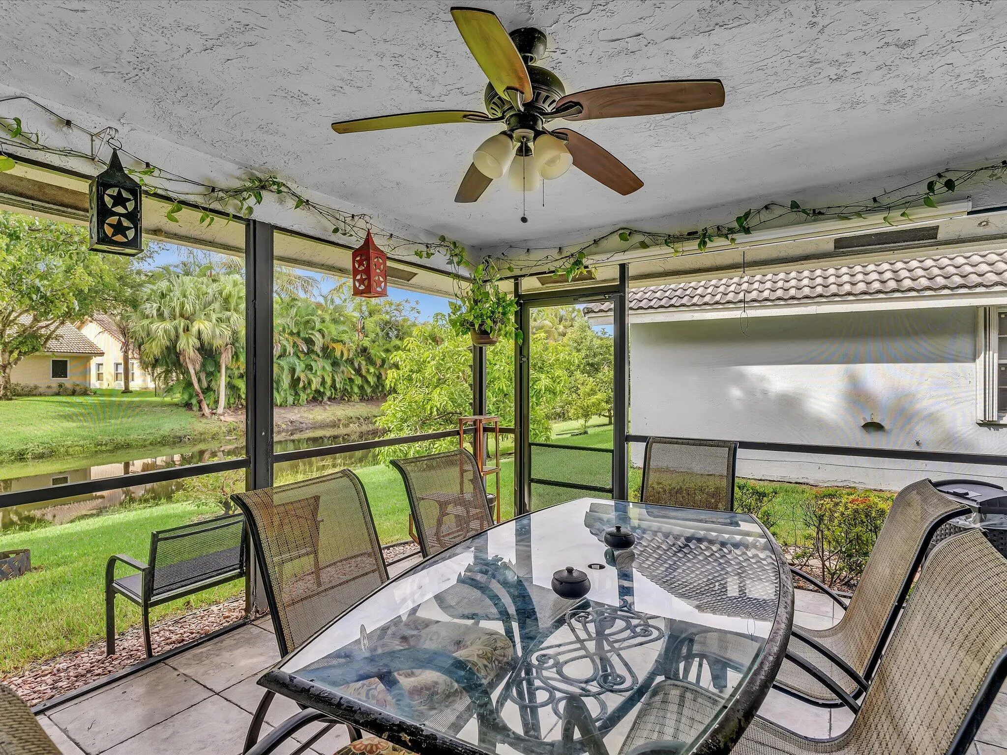 Screened-in patio featuring a ceiling fan, concrete flooring, and water frontage
