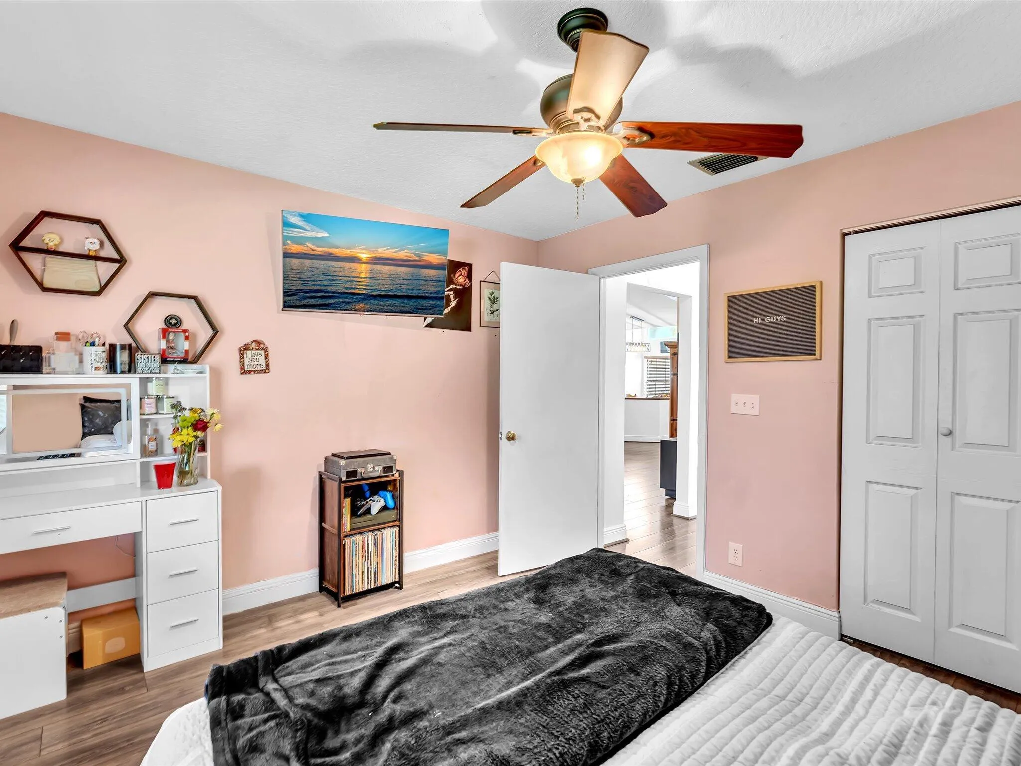 Wood-finish flooring, ceiling fan with integrated lighting, bi-fold closet doors, and a paneled interior door
