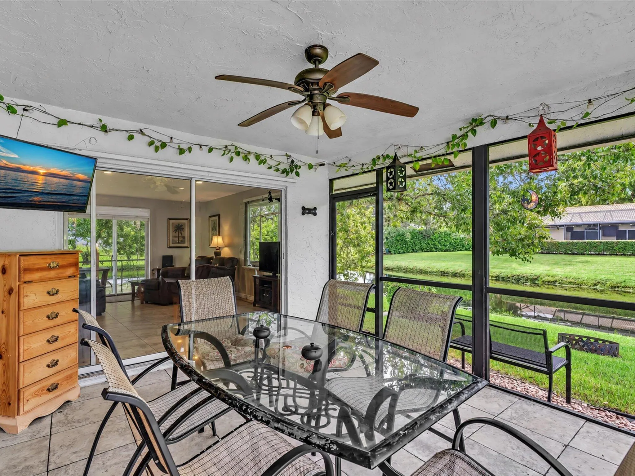 Screened patio with a ceiling fan, tiled flooring, and a glass-top table